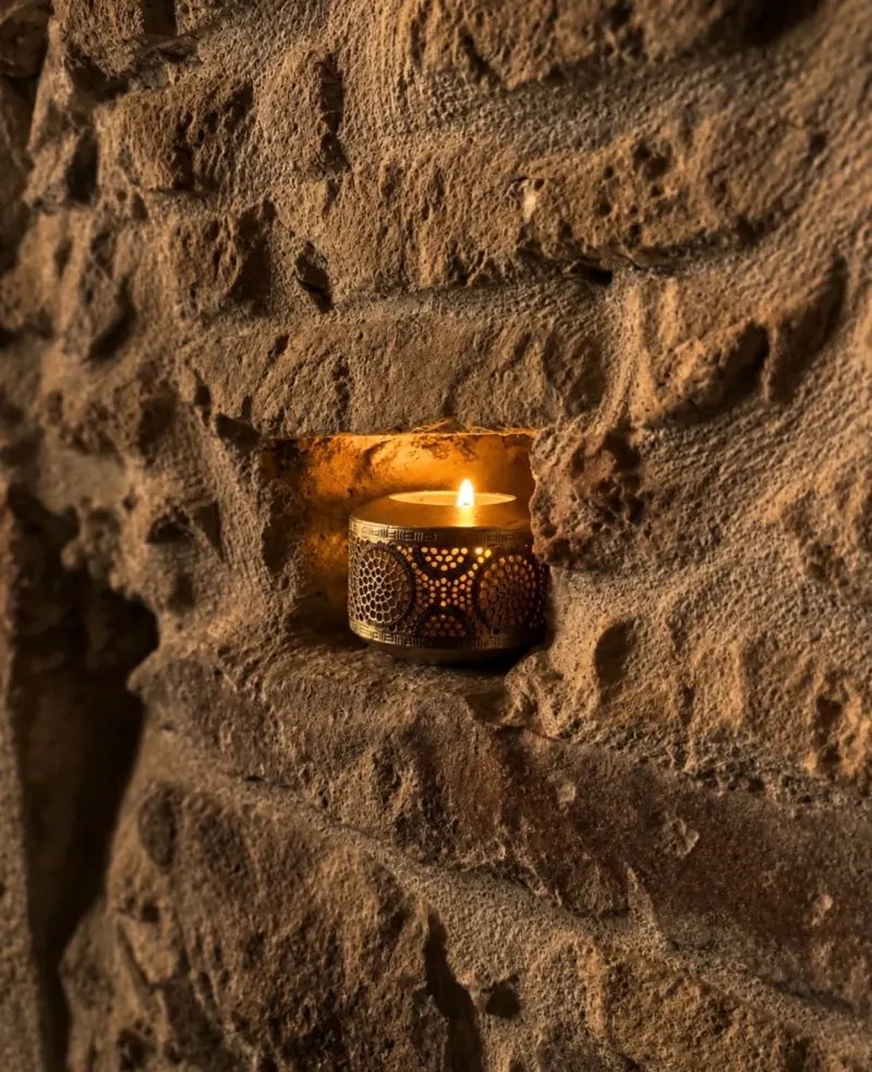 A candle in a niche of the stone wall